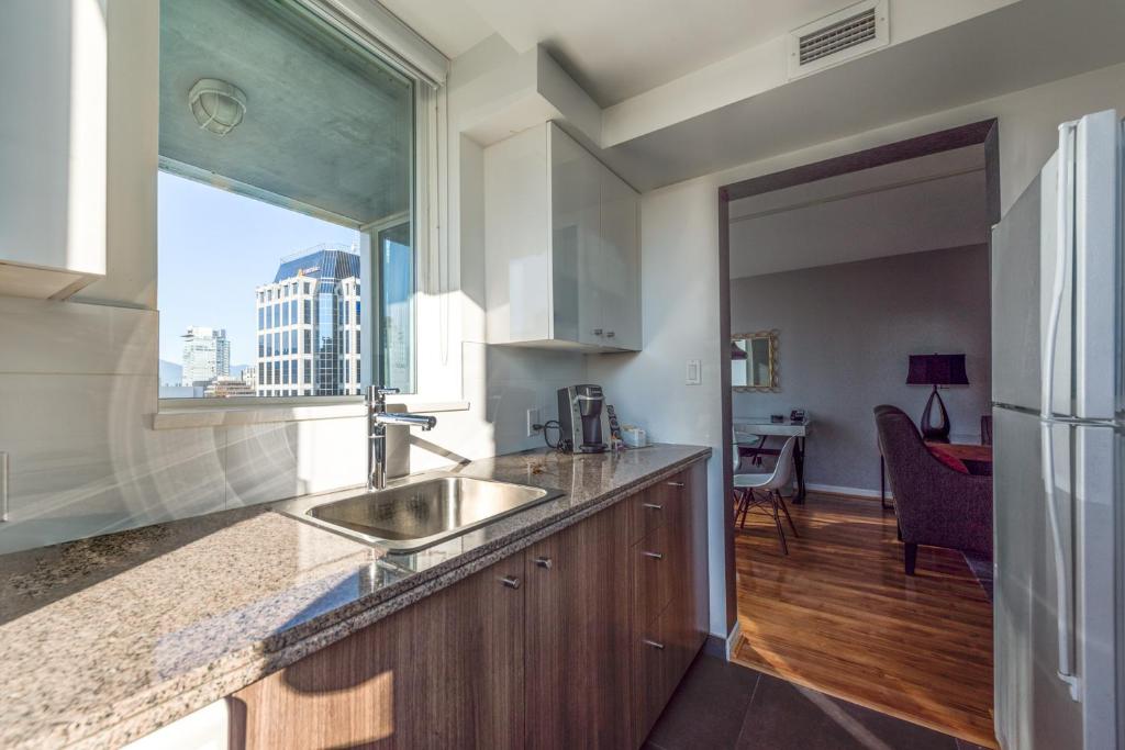 a kitchen with a sink and a large window at Carmana Hotel & Suites in Vancouver