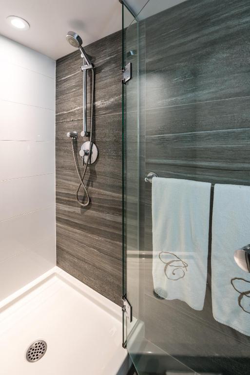 a bathroom with a shower with a glass door at Carmana Hotel & Suites in Vancouver