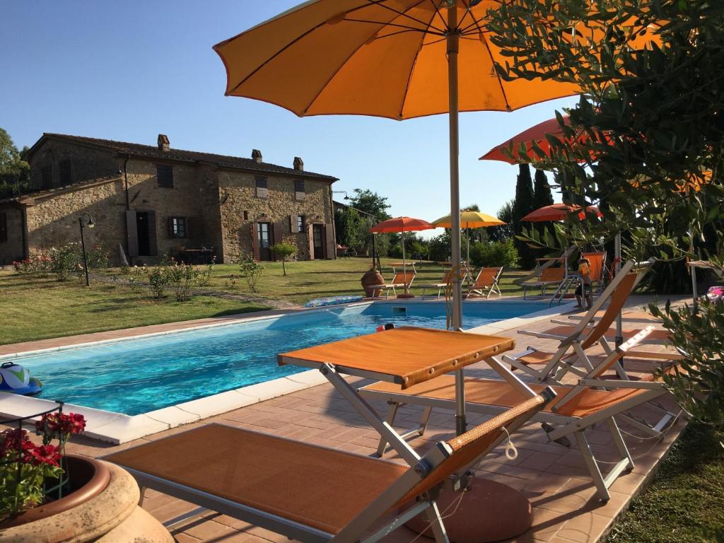 uma mesa e cadeiras com um guarda-sol ao lado de uma piscina em Farmhouse Gello by ToscanaTour em Montecatini Val di Cecina