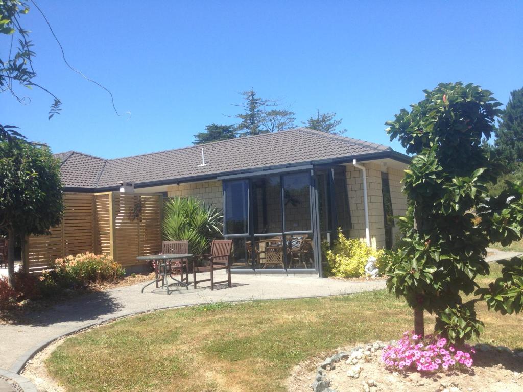 a house with a table and chairs in the yard at Silverdale Garden Studio in Orewa