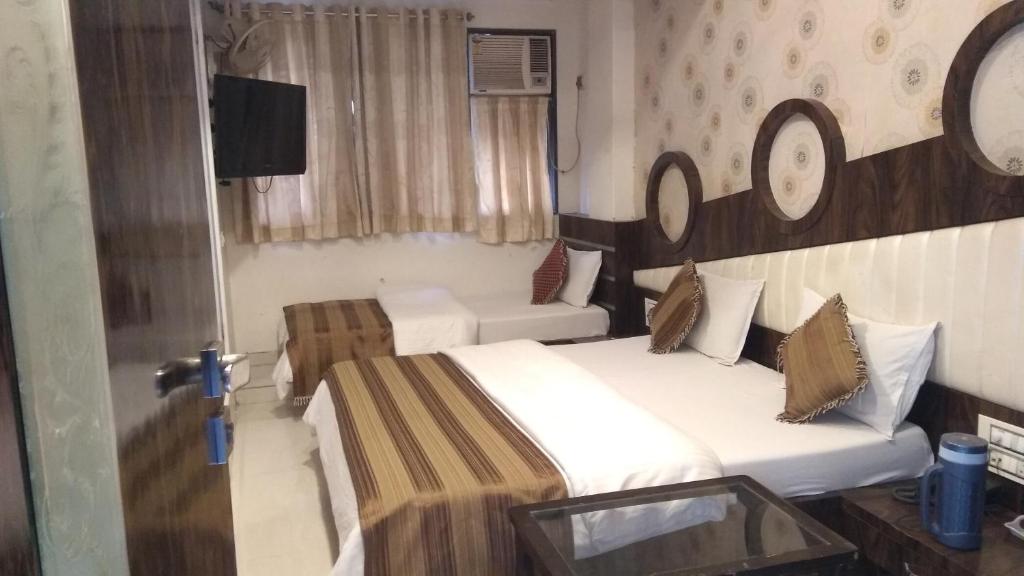 a hotel room with two beds and a tv at Hotel Navi Mumbai in Navi Mumbai