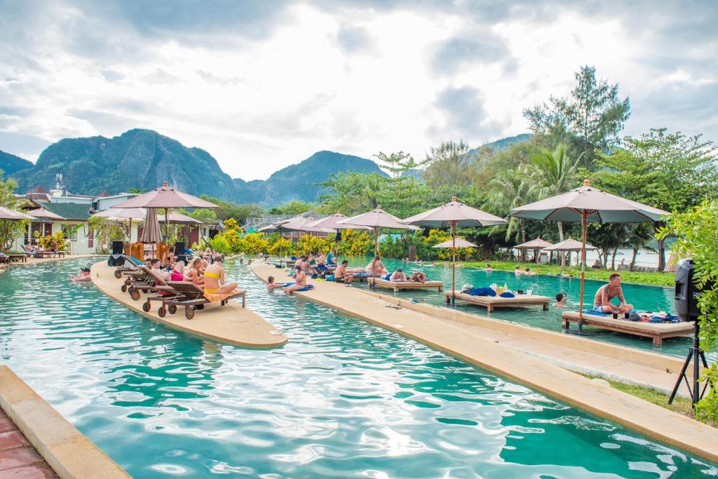 uma piscina num resort com pessoas sentadas em bancos em PP Charlie Beach Resort em Phi Phi Don