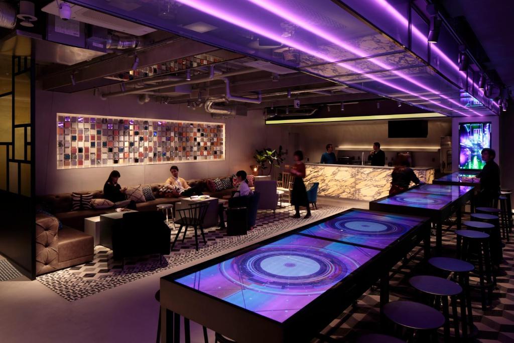 a bar with purple lights in a room with people at The Millennials Shibuya in Tokyo