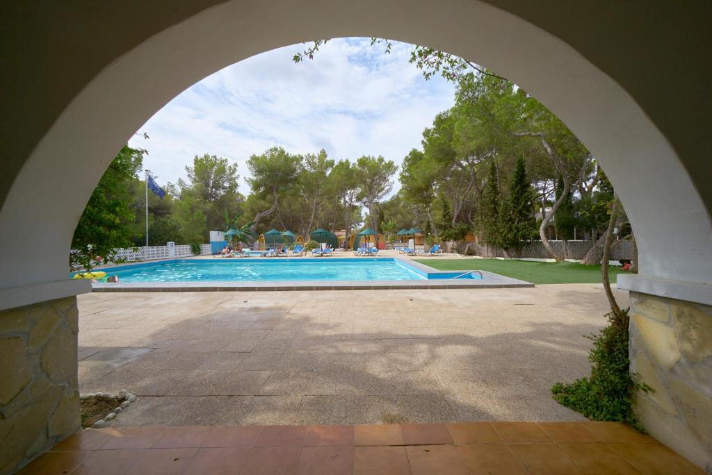 an archway over a swimming pool in a yard at Camping Escana in Es Cana