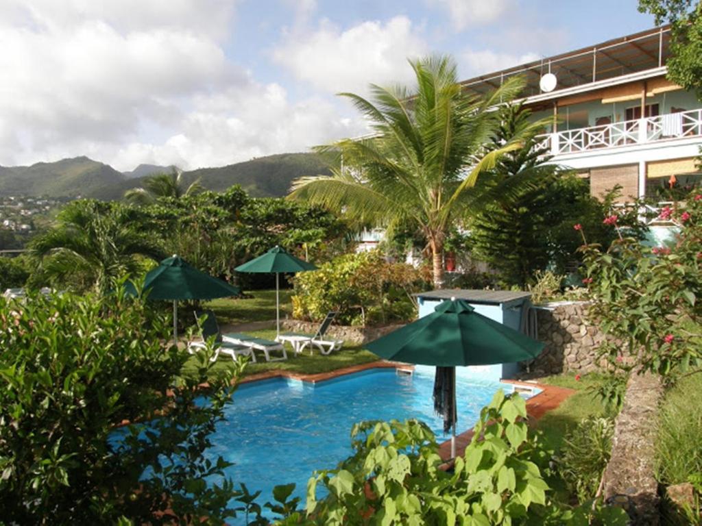 a pool with umbrellas and chairs and a building at Tamarind Tree Hotel in Salisbury