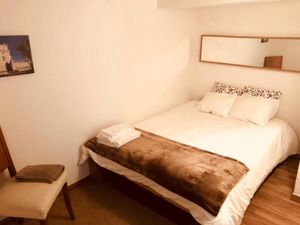 リスボンにあるLisbon Secret & Graca Apartmentのベッドと椅子付きの小さな部屋です。