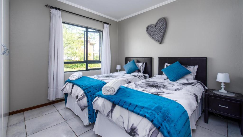 a bedroom with two beds and a window at JoziStay @ Jackal Creek Apartments in Roodepoort