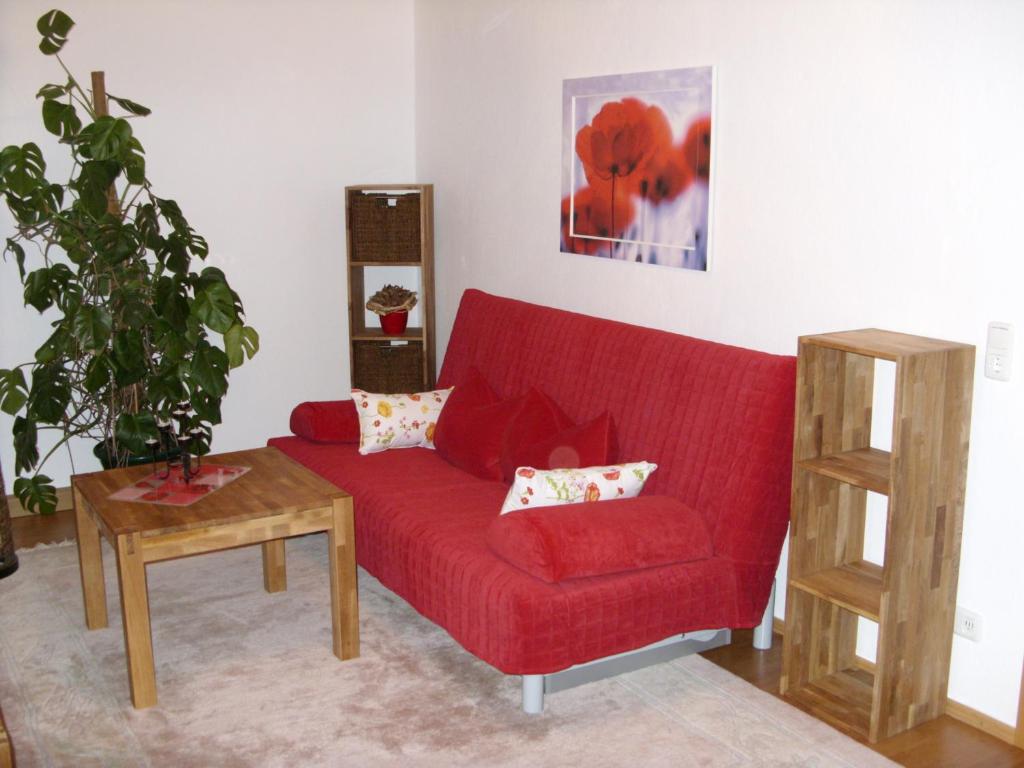 een rode bank in een woonkamer met een tafel bij Ferienwohnung Frenkel in Freital