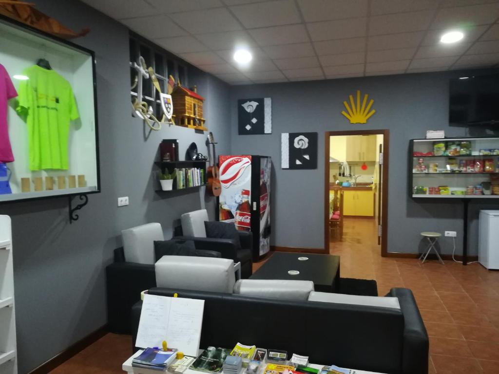 una sala de espera con sofá y TV en una tienda en Albergue O Bordón, en Cee