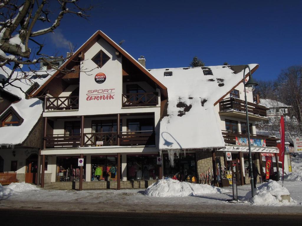 a large building with snow on the side of it at Pension Apartmány Sport Čermák in Harrachov