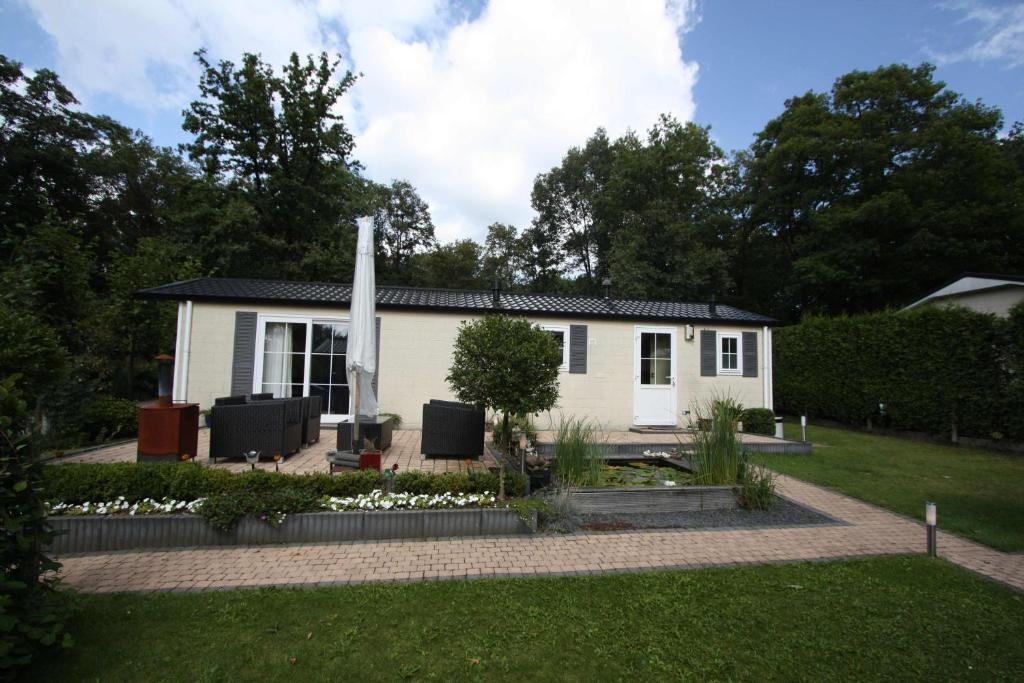 une petite maison blanche avec un jardin en face de celle-ci dans l'établissement Vakantiehuis Veluwe Wageningen, à Wageningue