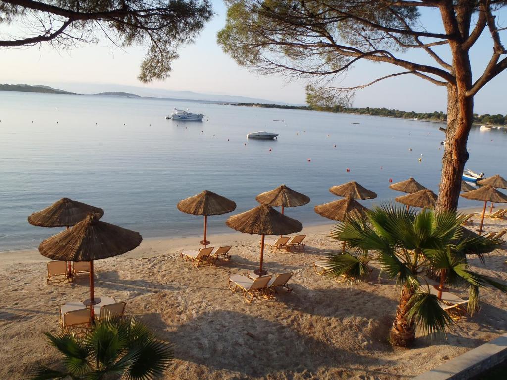 een strand met veel parasols en stoelen en het water bij Vergos Hotel in Vourvourou