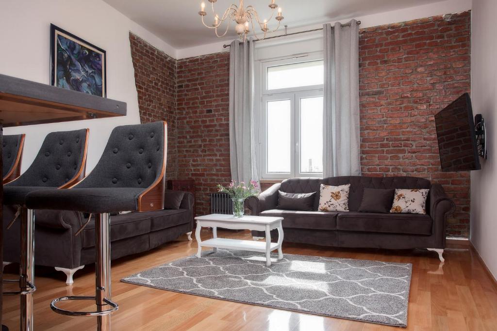 a living room with two couches and a brick wall at Core Apartments Zagreb in Zagreb