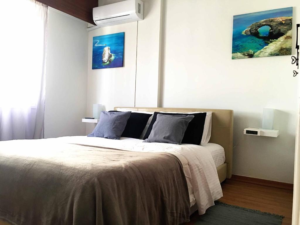 a bedroom with a bed with white sheets and blue pillows at Comfortable Engomi Apartment in Yukarı Lakatamya