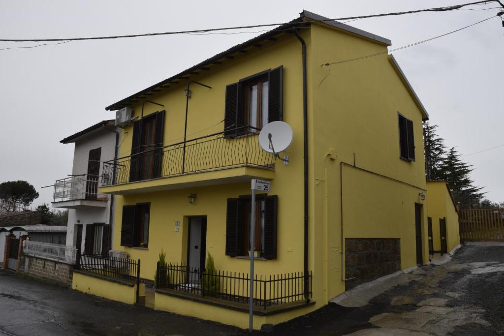 Una casa amarilla con un balcón en el lateral. en Casa di Bacco en Vetralla