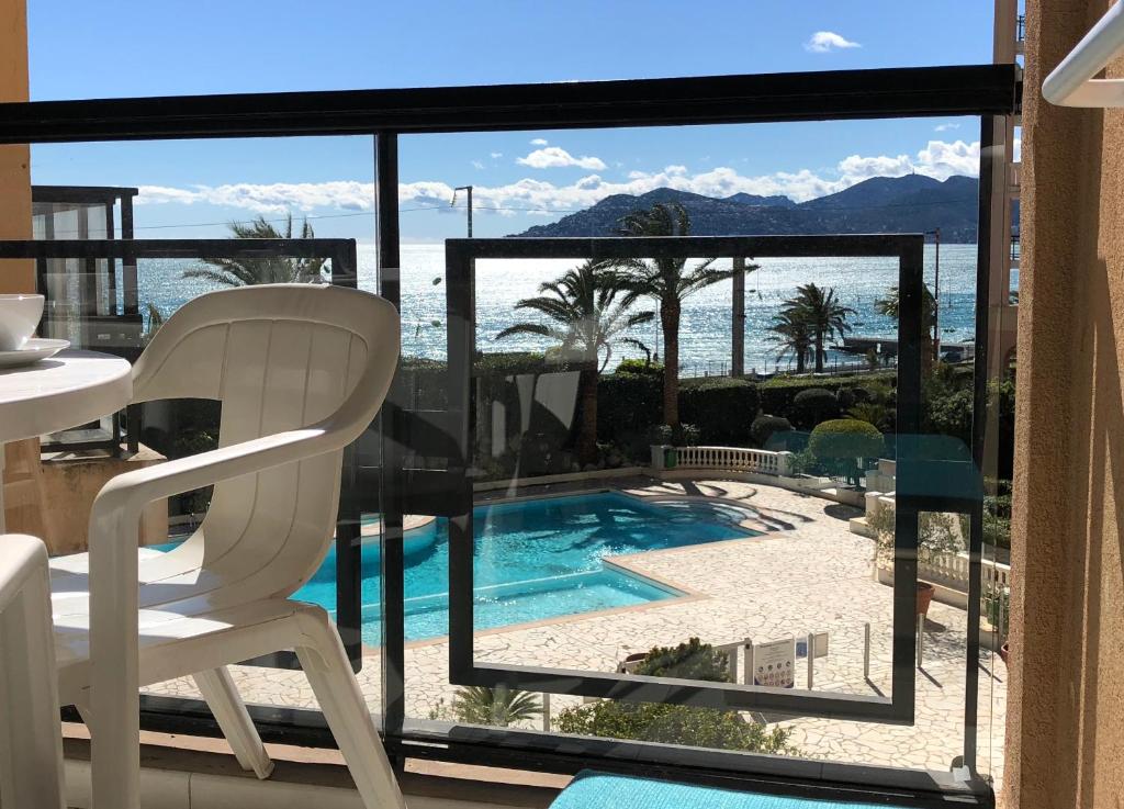 une chaise blanche assise sur un balcon avec vue sur la piscine dans l'établissement Cannes vue mer, à Cannes