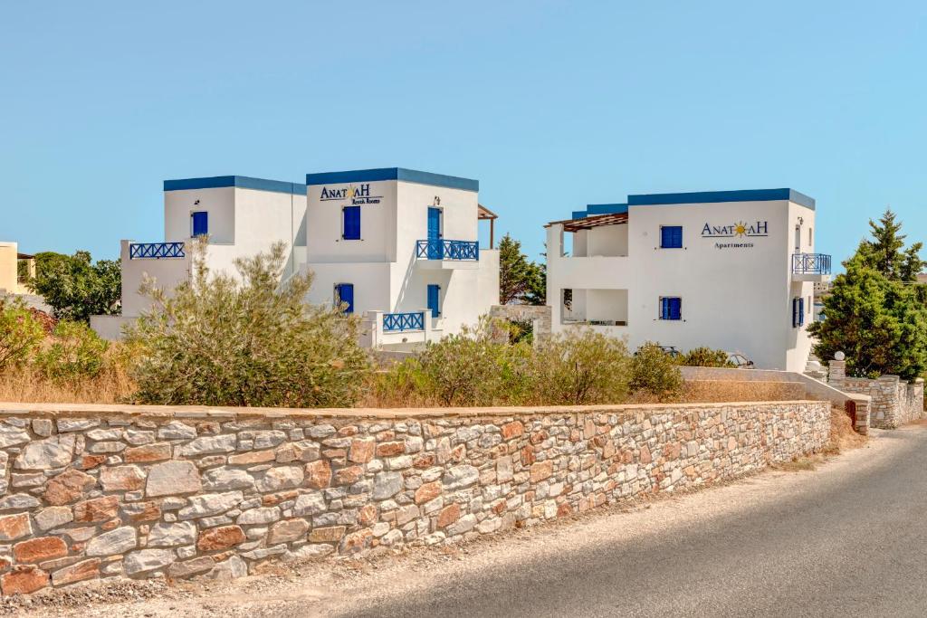 a stone wall in front of some white buildings at Anatoli in Azolimnos Syros