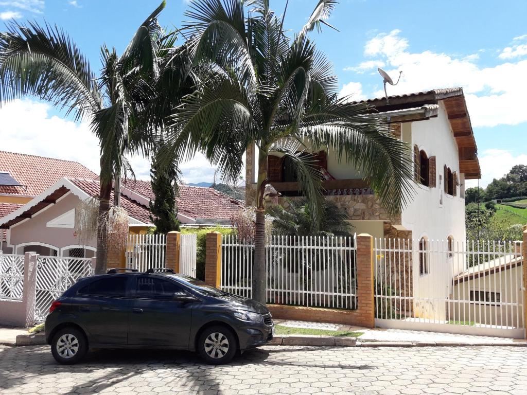 a car parked in front of a house with palm trees at Casa para temporada in São Bento do Sapucaí