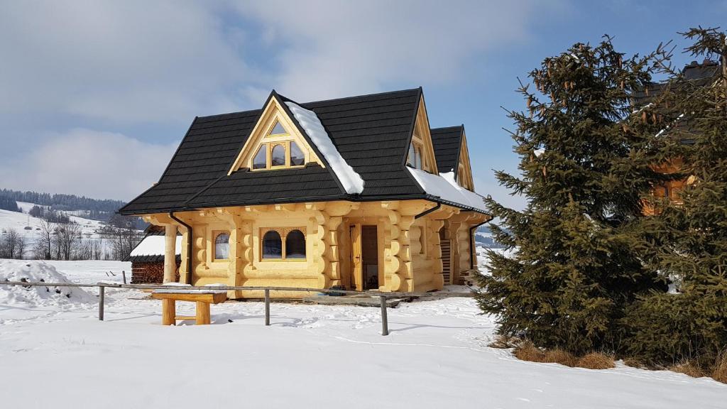 ein Holzhaus mit schwarzem Dach im Schnee in der Unterkunft Domek w Białce in Białka Tatrzańska