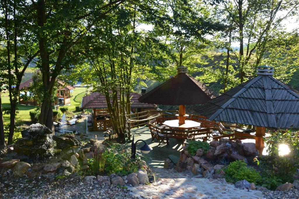 上米拉諾瓦茨的住宿－Guest House Etno selo Trbović，庭院内带桌子和遮阳伞的庭院