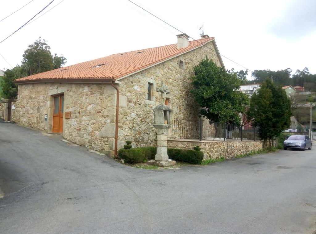 ein altes Steinhaus mit einem davor geparkt in der Unterkunft O Cruceiro in Boiro