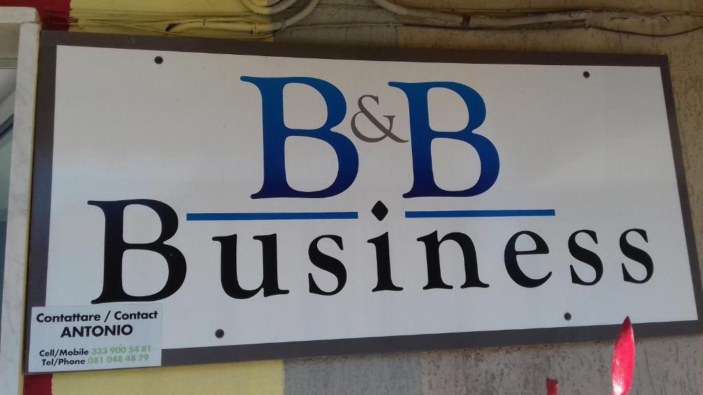 a sign for a big business hanging on a wall at B&B Business in Casalnuovo di Napoli