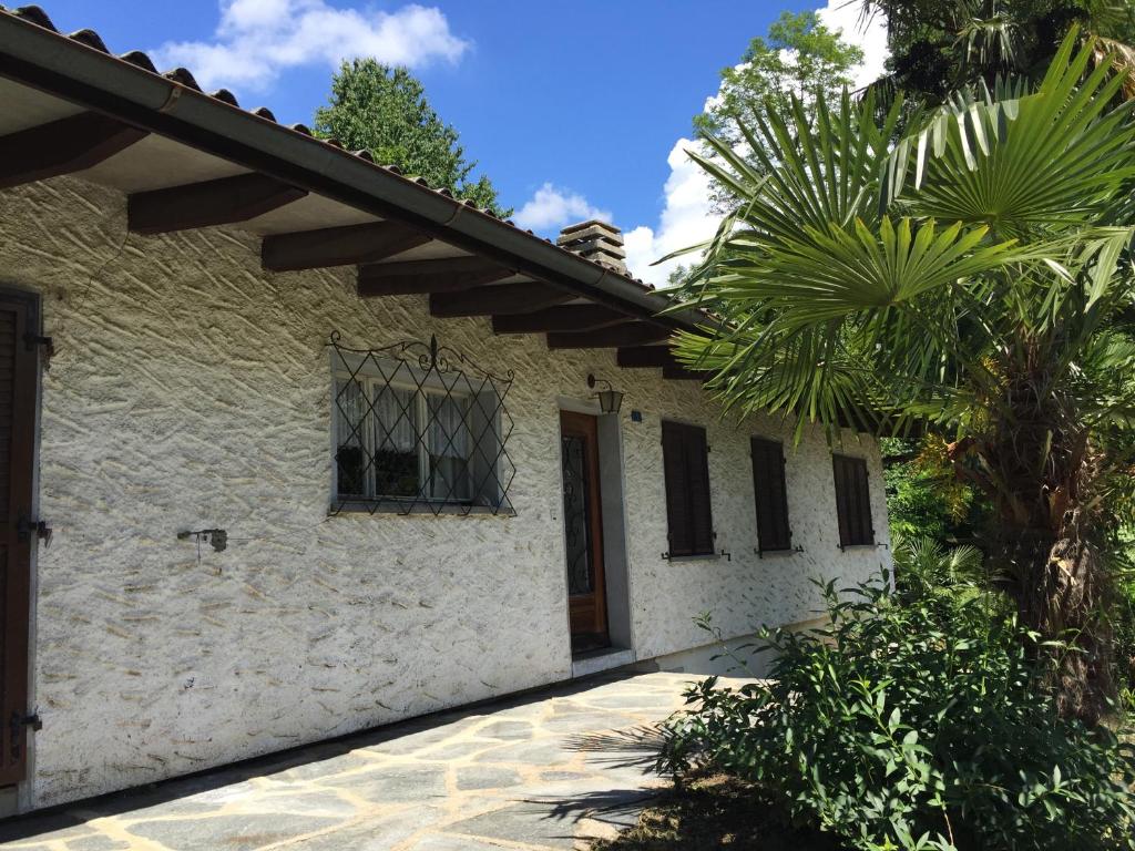 a white house with a door and a palm tree at Casa Parentela in Ligornetto