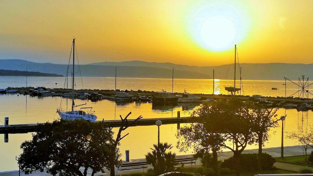 a sunset over a marina with boats in the water at Obala Apartment & Studios in Malinska