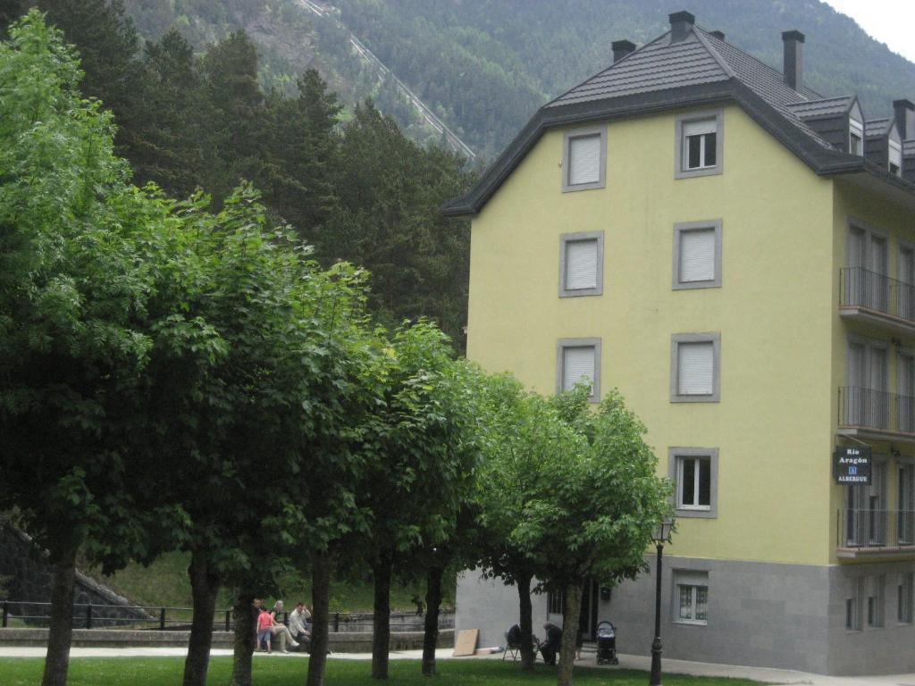 un edificio amarillo con árboles delante de él en Albergue Turístico Rio Aragon en Canfranc-Estación