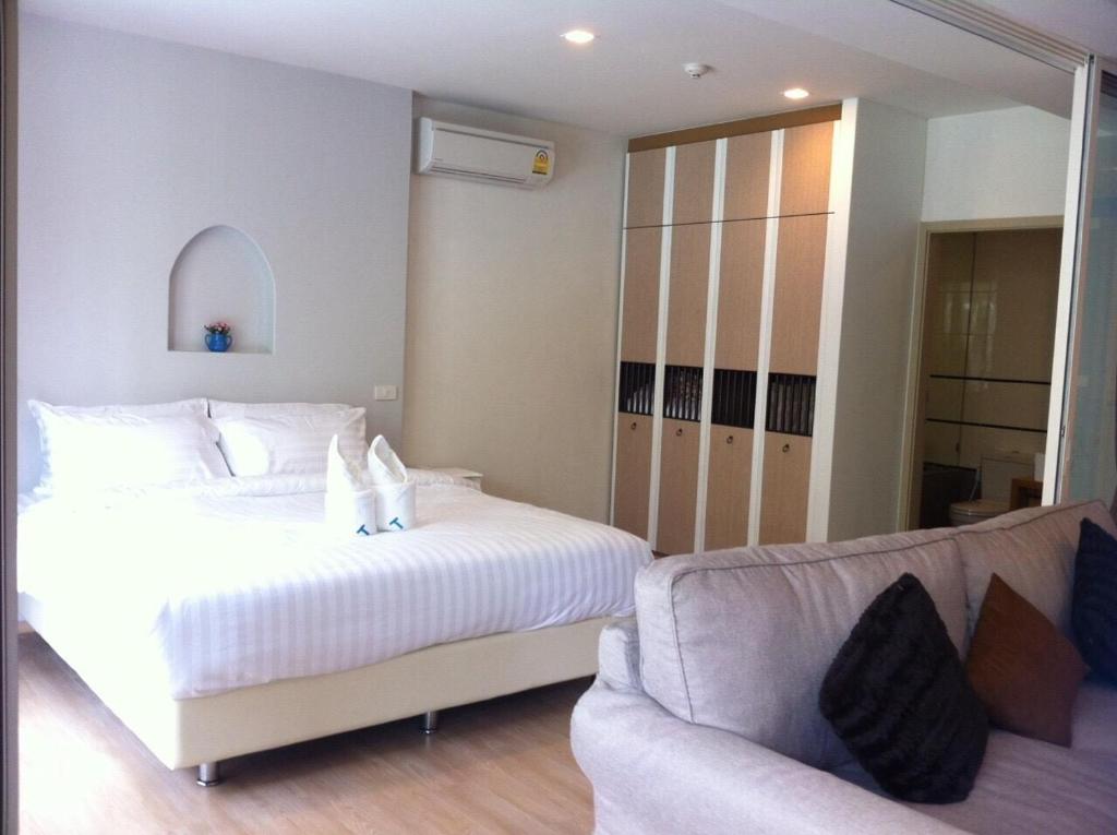 Un dormitorio con una cama blanca y un sofá. en BanSanKram by Patsara, en Cha Am