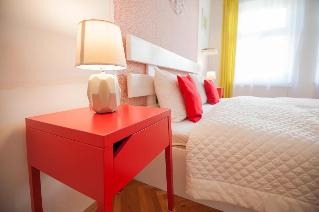 uma mesa de cabeceira vermelha com um candeeiro numa mesa vermelha ao lado de uma cama em Spacious Stylish Apartment in Old Town em Sibiu