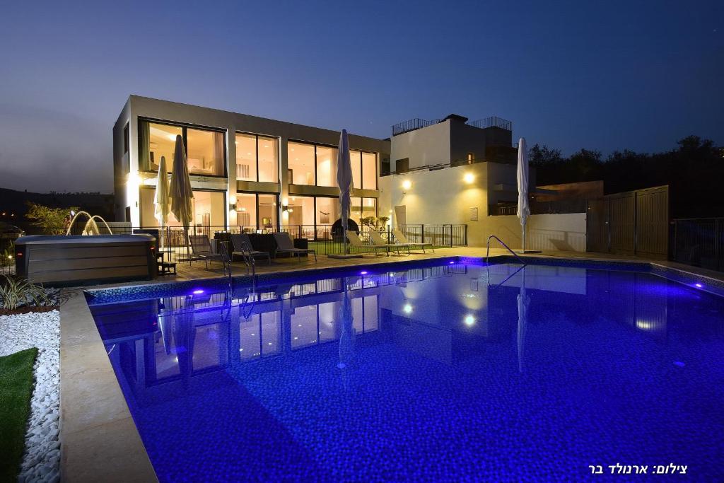 a swimming pool in front of a house at night at Villa J in Migdal