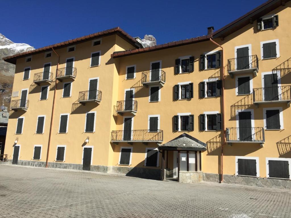 - un grand bâtiment jaune avec des fenêtres et des balcons dans l'établissement Residence Redicervinia, à Breuil-Cervinia