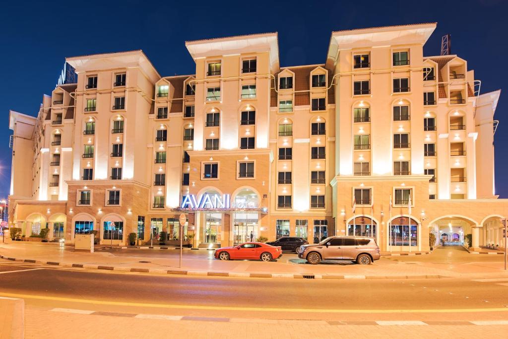 un grand bâtiment avec des voitures garées devant lui dans l'établissement Avani Deira Dubai Hotel, à Dubaï