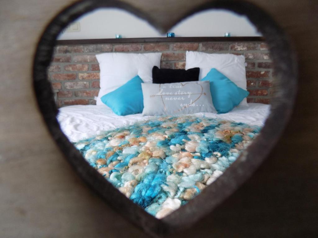 a heart shaped mirror reflecting a bed with pillows at (La parenthese) in Hombourg