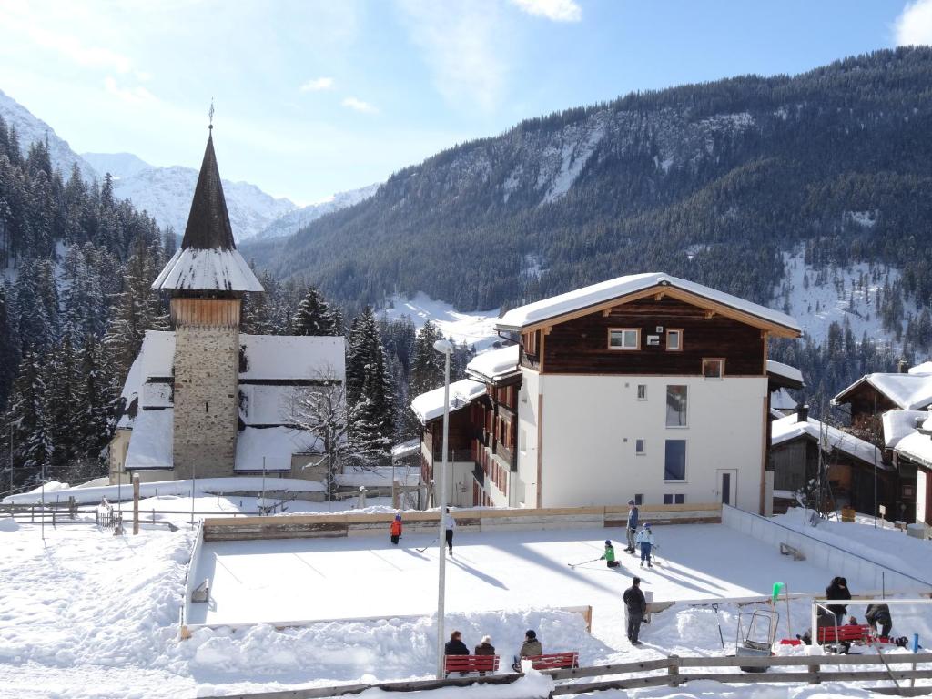 ein Gebäude mit einer Eislaufbahn im Schnee neben einer Kirche in der Unterkunft Apartment Turmzimmer in Langwies