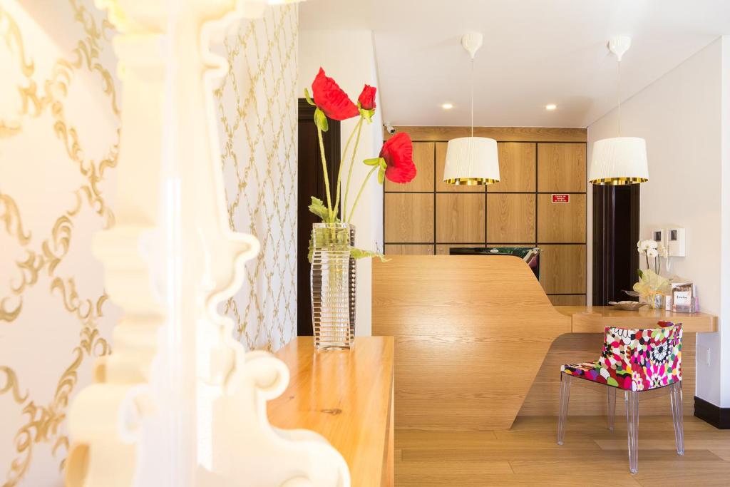 uma sala de jantar com uma mesa e um vaso com flores vermelhas em Cerca Design House no Fundo