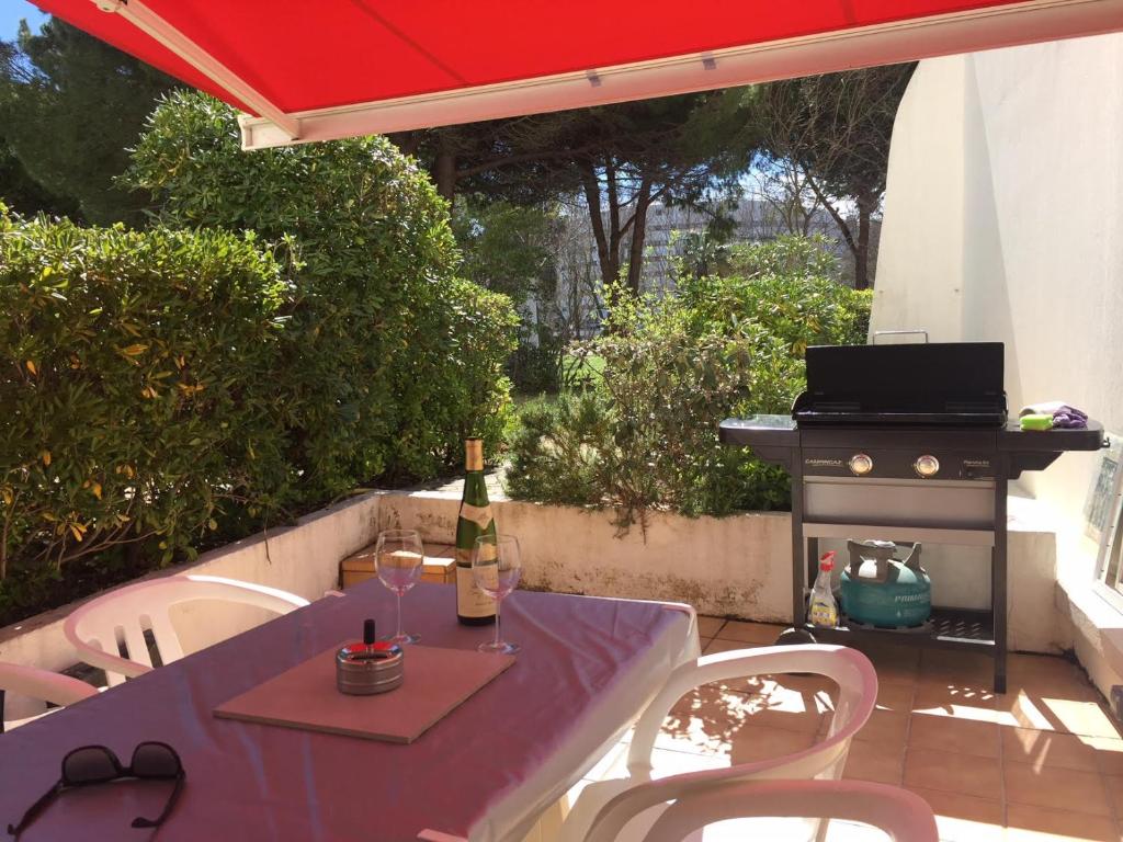 einen Tisch und Stühle mit einem Sonnenschirm und einem Grill in der Unterkunft studio parking 5 min de la plage in La Grande-Motte