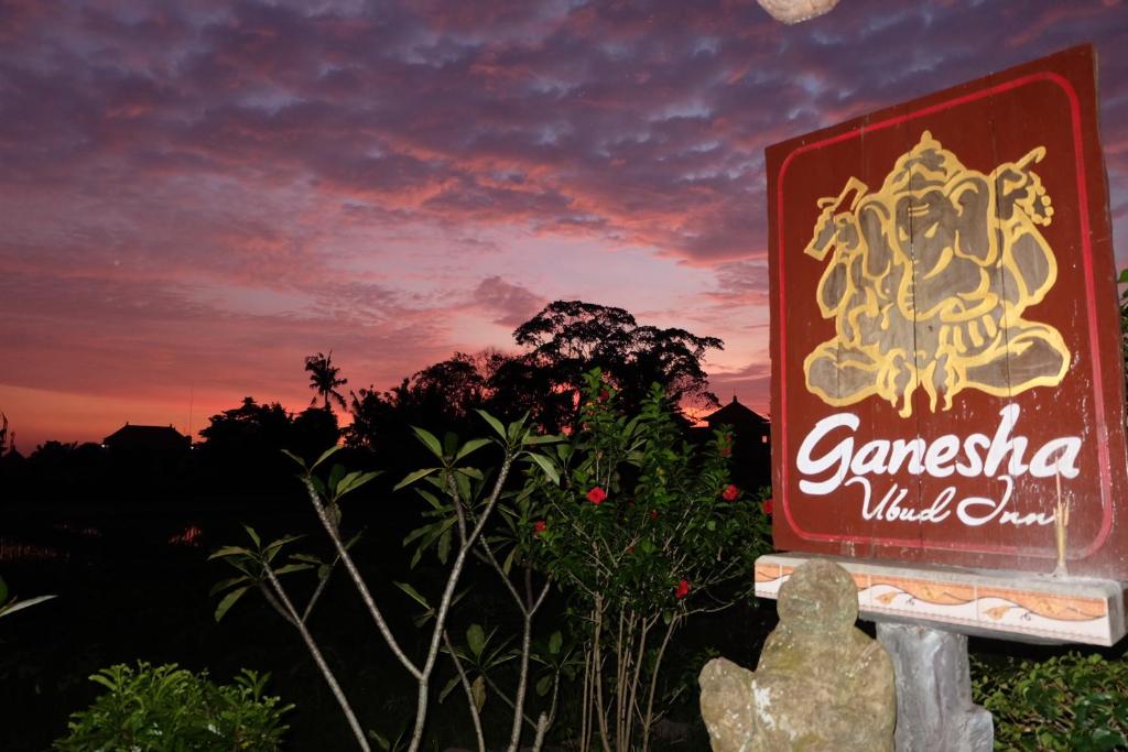 una señal para un restaurante con una puesta de sol en el fondo en Ganesha Ubud Inn, en Ubud