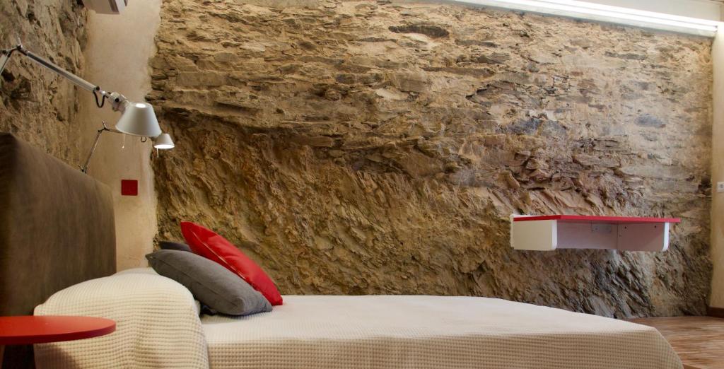 - une chambre avec un lit et un mur en pierre dans l'établissement B&B Mare di Fuori, à Stintino