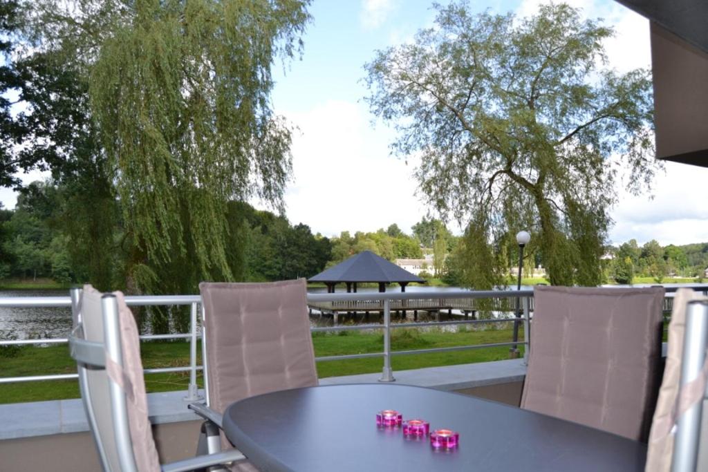 a table and chairs on a patio with a view of the water at la terrasse du lac in Vielsalm