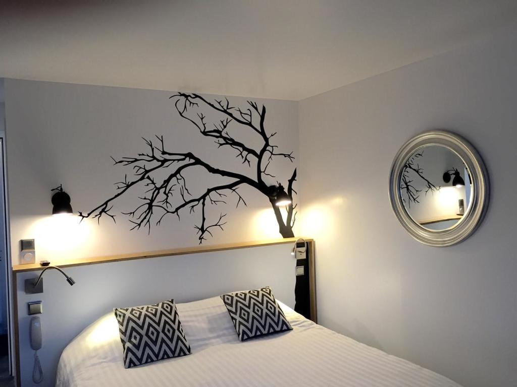 a bedroom with a bed with a branch on the wall at Hôtel-Restaurant La Mascotte in La Baule