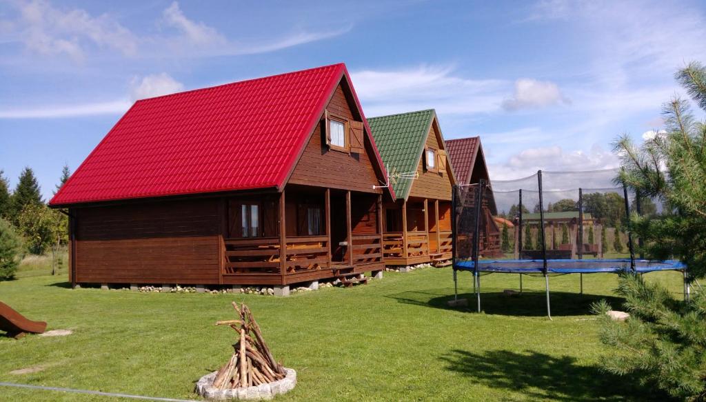 een groot houten huis met een rood dak en een speeltuin bij Trzy Kolory Jezierzany in Jezierzany