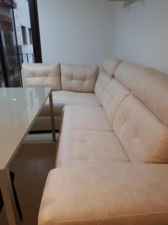 sala de estar con sofá blanco y mesa de cristal en Piso Josemi, en Monachil