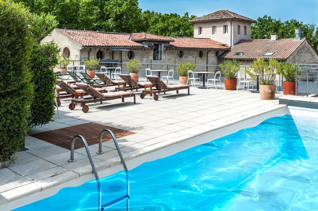 a swimming pool with chairs and a house at Hôtel Cloitre Saint Louis Avignon in Avignon