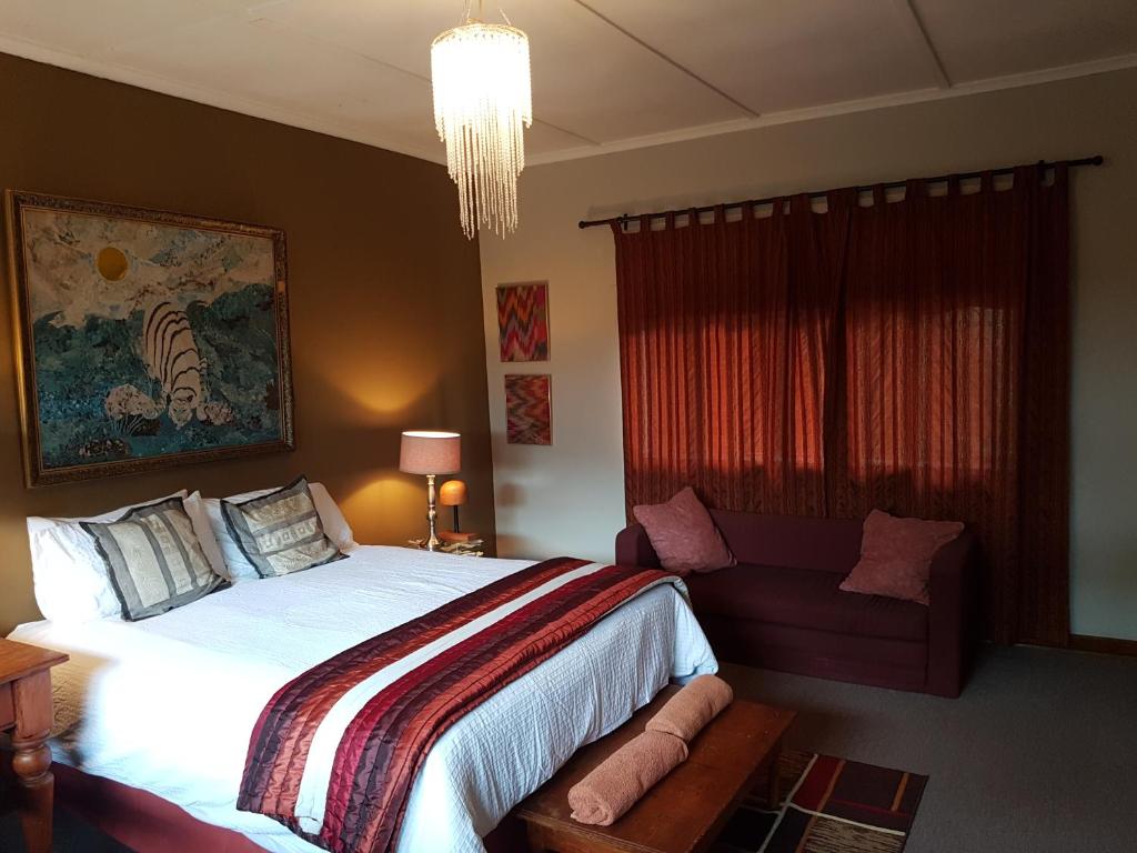 a bedroom with a large bed and a chair at Burnham Road Suite Guest House in Bulawayo