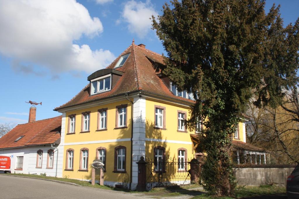 a yellow and white house with a brown roof at Art-be-and-b Appartement -Studios in Riegel am Kaiserstuhl
