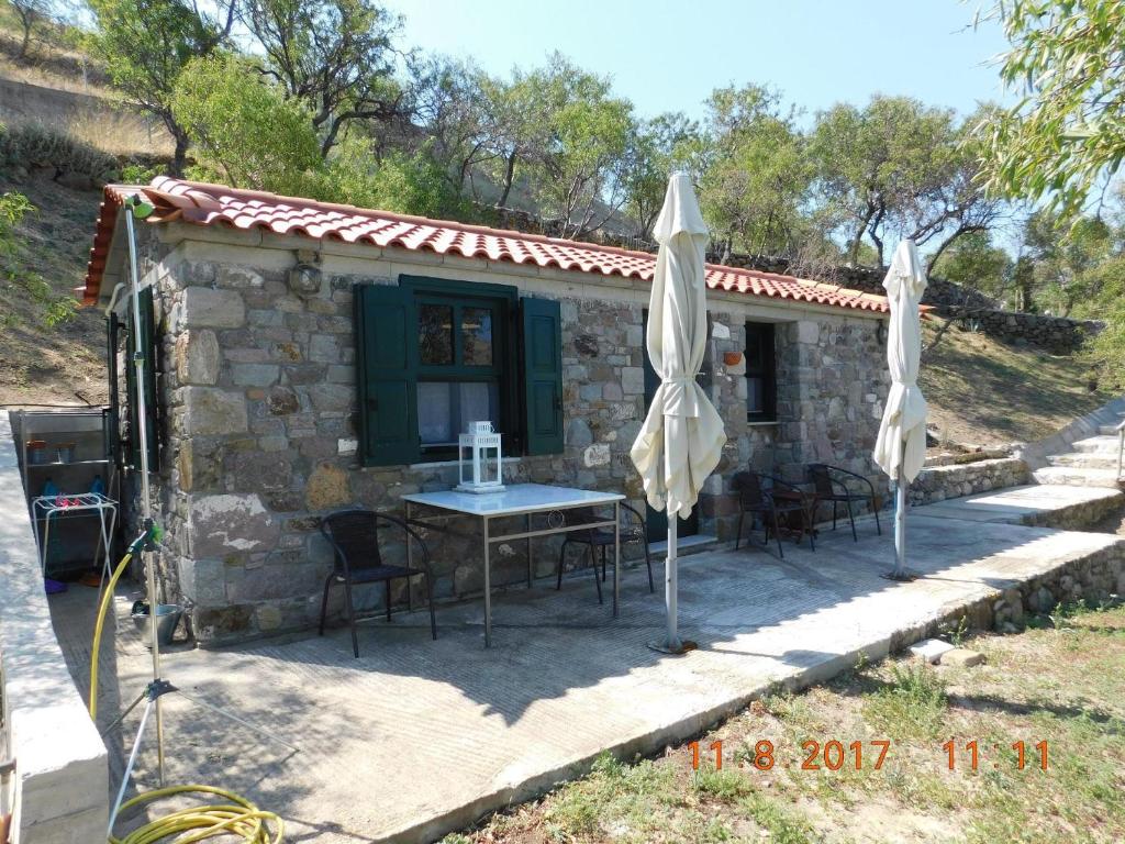 a stone house with a table and chairs and umbrellas at Stone cottage for couple in Thános