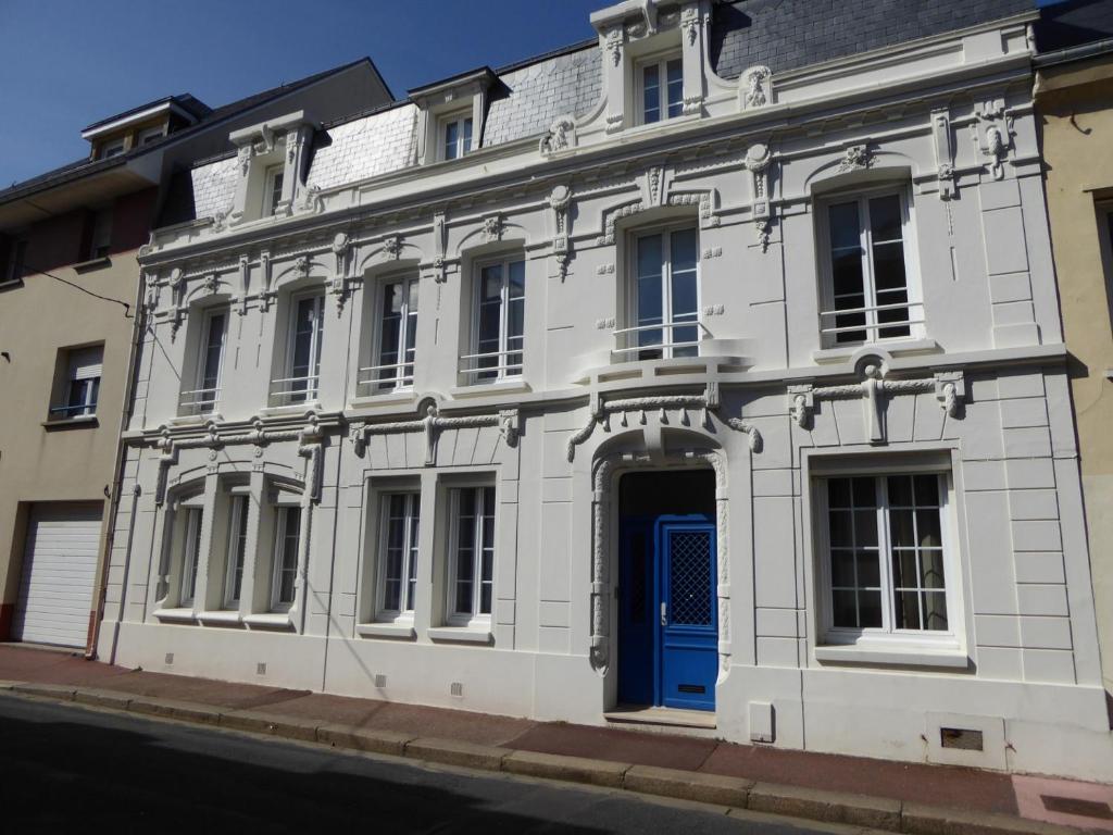 un edificio blanco con una puerta azul en una calle en B&B A La Maison Blanche en Fécamp