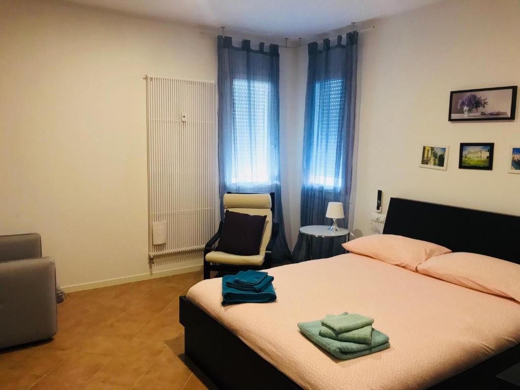 a bedroom with a bed and a chair and windows at ApartmentsPadova in Padova